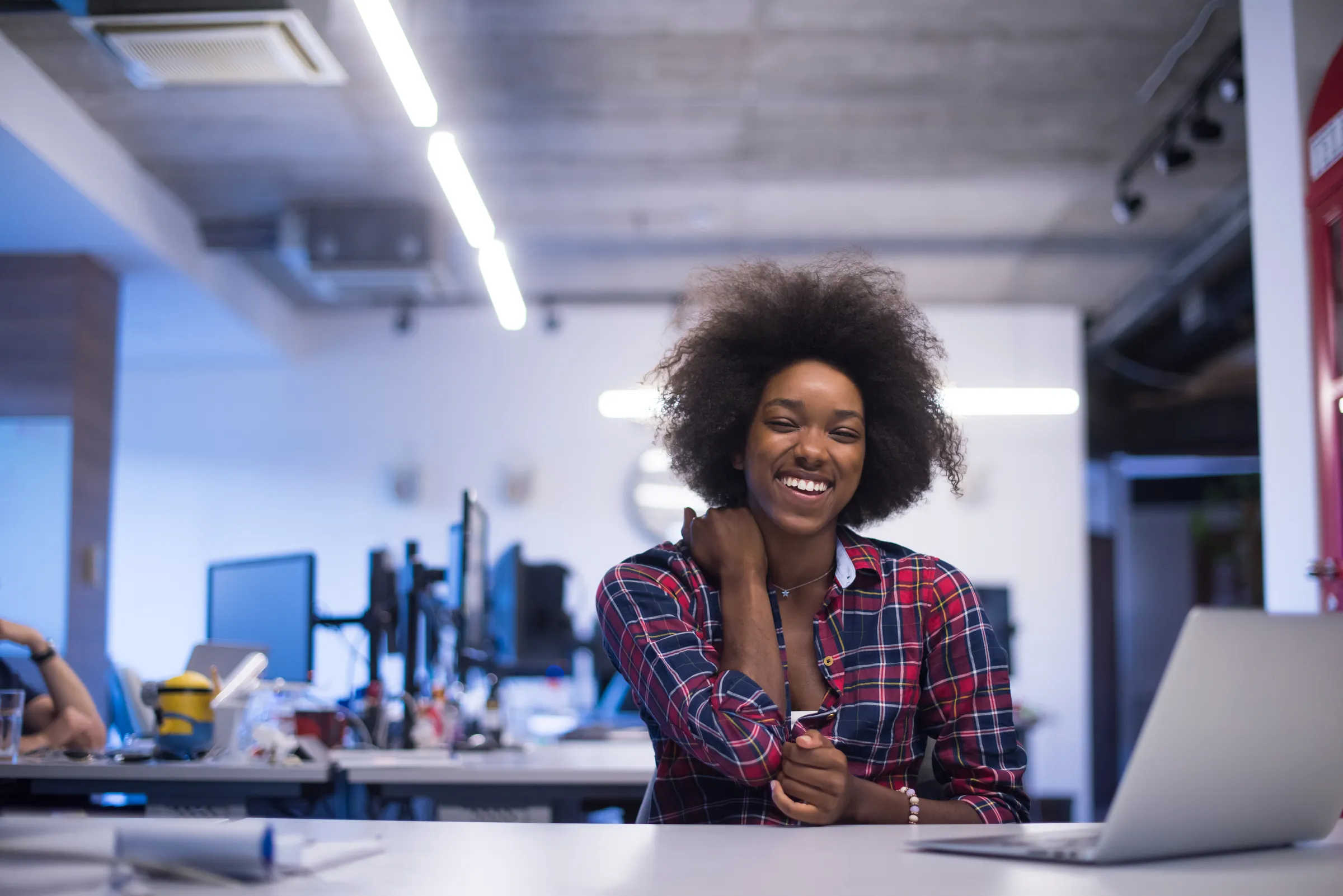 Jeune femme souriante, future ingénieure en informatique, dans un espace de coworking tech animé